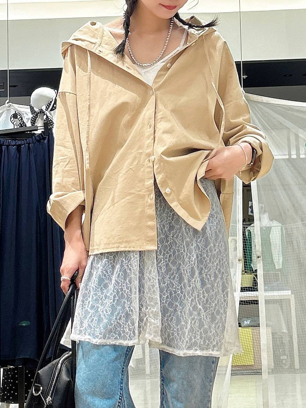 ブラック系のボストンバッグ、ブラック系のスニーカー、ブルー系のデニムパンツを着用したレディースの春コーディネートの2枚目の写真