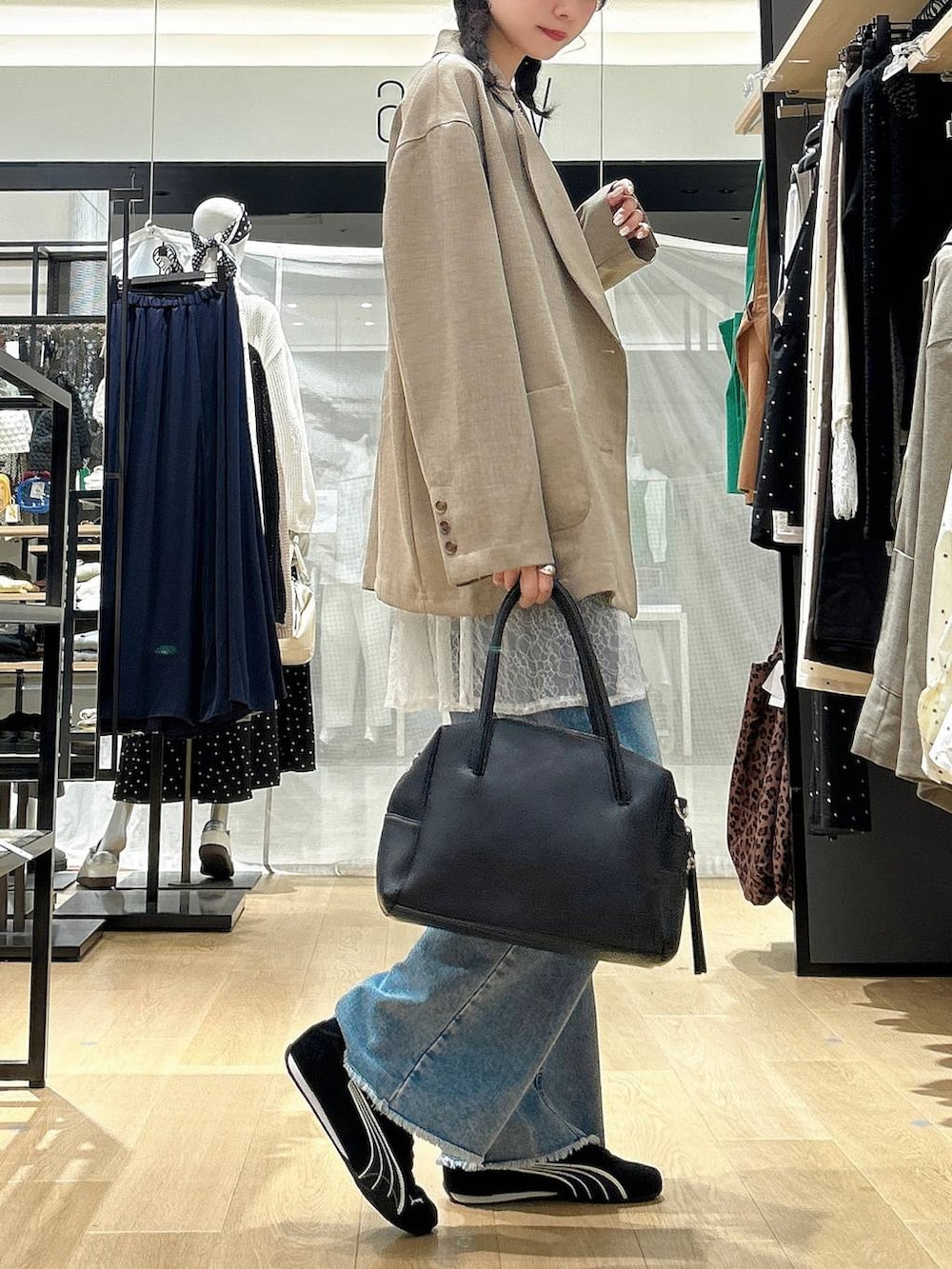 ブラック系のボストンバッグ、ブルー系のデニムパンツ、ブラウン系のテーラードジャケットを着用したレディースの春コーディネートの2枚目の写真