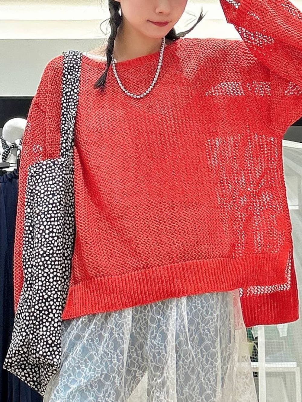 ブラック系のスニーカー、ブルー系のデニムパンツ、レッド系のニット/セーターを着用したレディースの春コーディネートの2枚目の写真