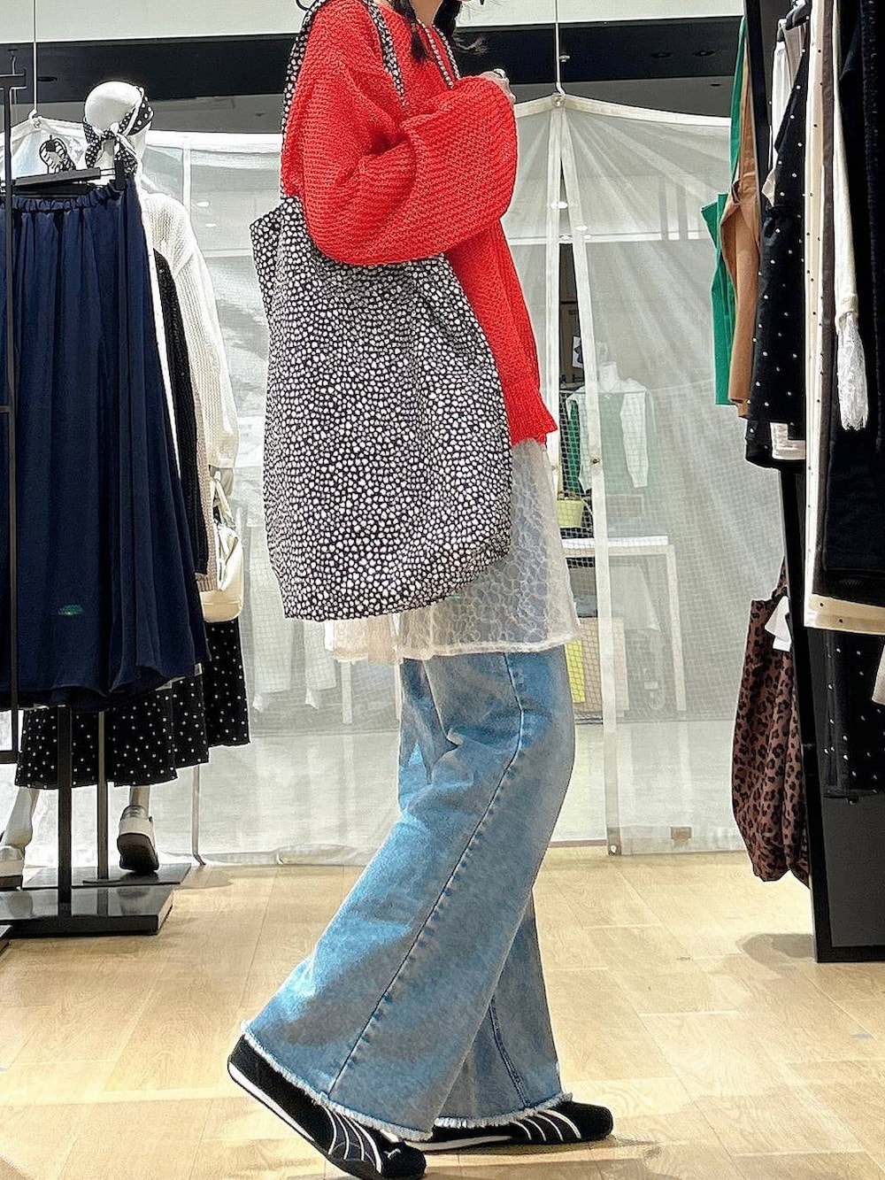 ブラック系のスニーカー、ブルー系のデニムパンツ、レッド系のニット/セーターを着用したレディースの春コーディネートの3枚目の写真