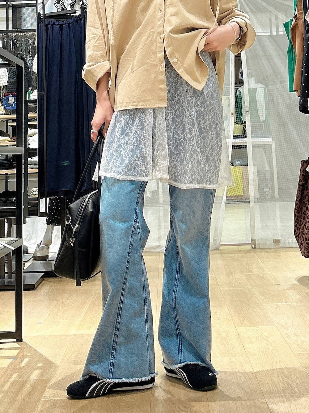 ブラック系のボストンバッグ、ブラック系のスニーカー、ブルー系のデニムパンツを着用したレディースの春コーディネートの3枚目の写真