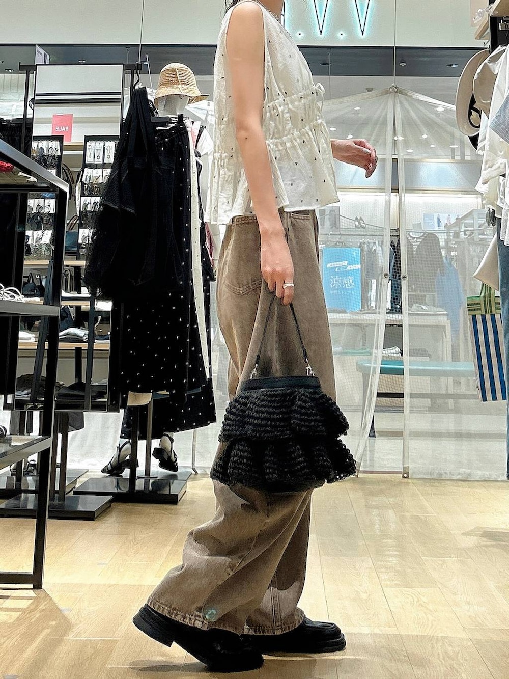 ブラウン系のデニムパンツ、ブラック系のショルダーバッグ、ホワイト系のその他トップスを着用したレディースの夏コーディネートの4枚目の写真