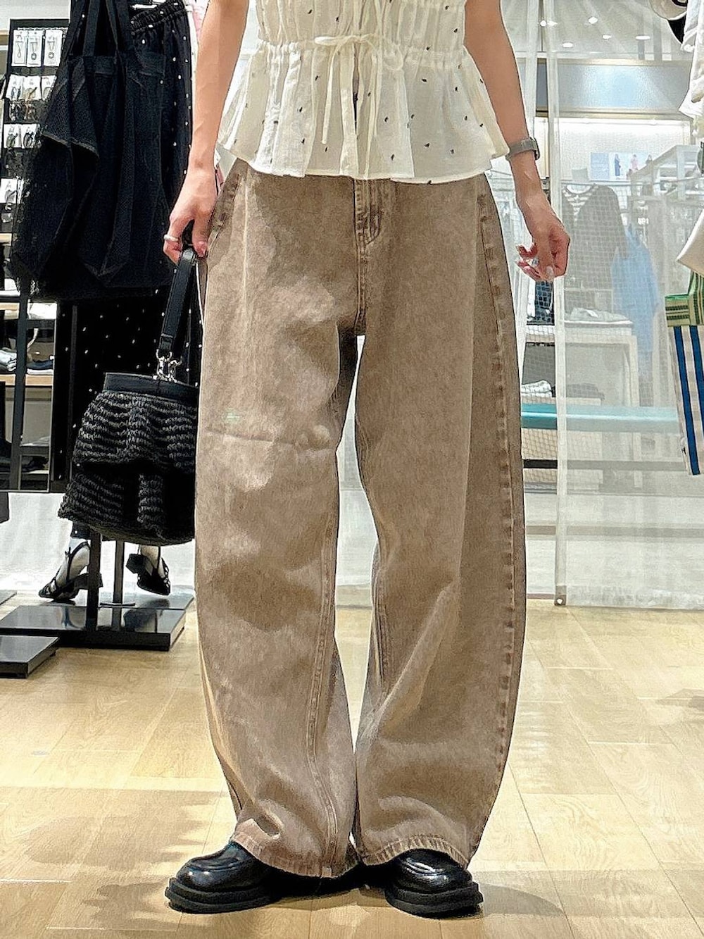 ブラウン系のデニムパンツ、ブラック系のショルダーバッグ、ホワイト系のその他トップスを着用したレディースの夏コーディネートの3枚目の写真