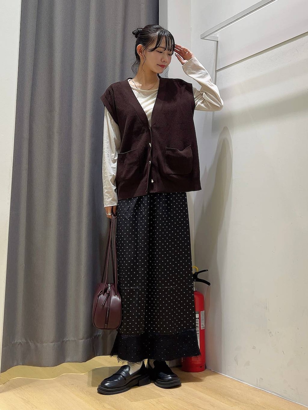レッド系のボストンバッグ、ベージュ系のTシャツ/カットソー、その他のスカートを着用したレディースの秋コーディネートの2枚目の写真