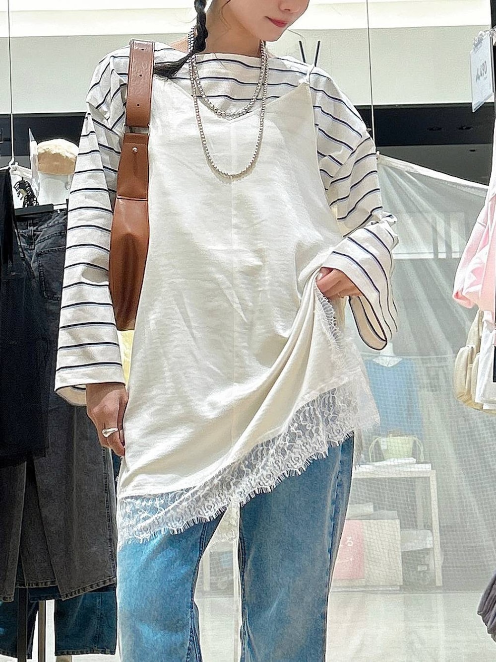 ブラウン系のショルダーバッグ、ブルー系のデニムパンツ、ベージュ系のワンピースを着用したレディースの冬コーディネートの2枚目の写真