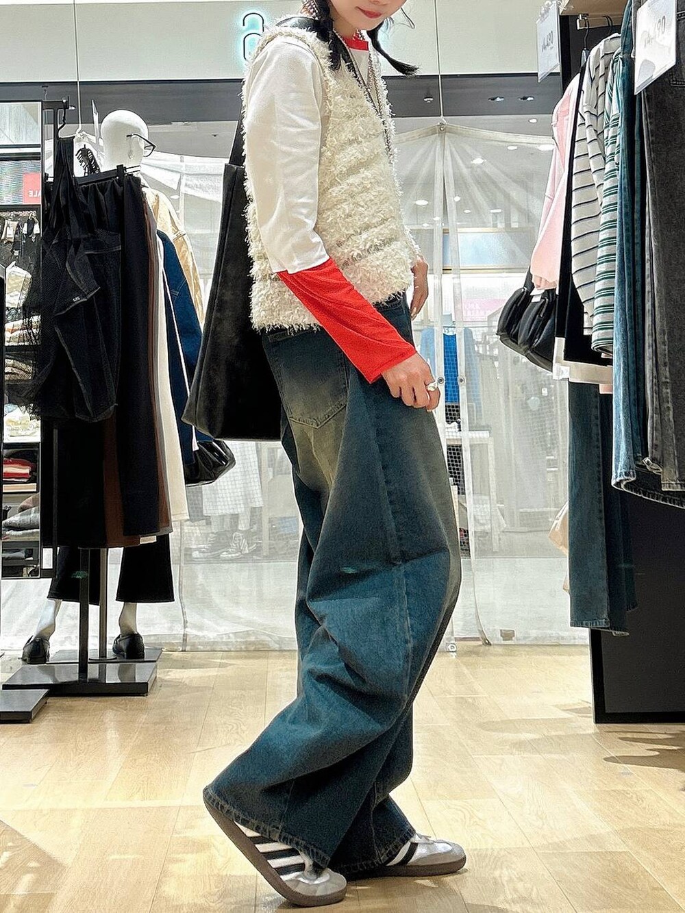 ブルー系のデニムパンツ、ブラック系のショルダーバッグ、ベージュ系のベストを着用したレディースの冬コーディネートの3枚目の写真