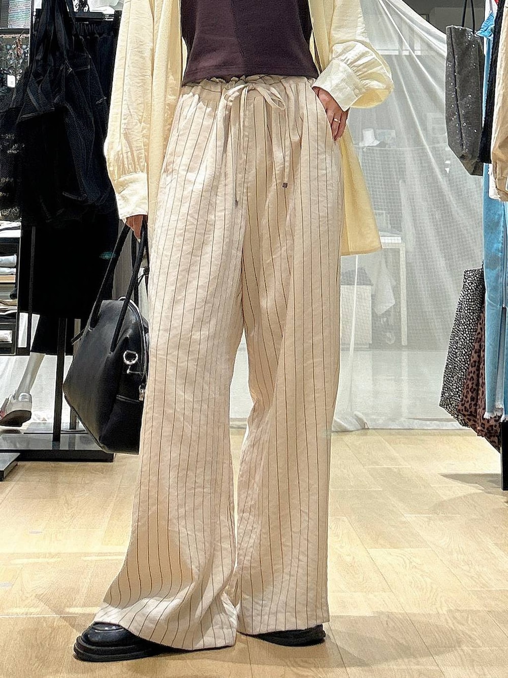 ブラック系のボストンバッグ、ホワイト系のその他パンツ、イエロー系のシャツ/ブラウスを着用したレディースの春コーディネートの2枚目の写真