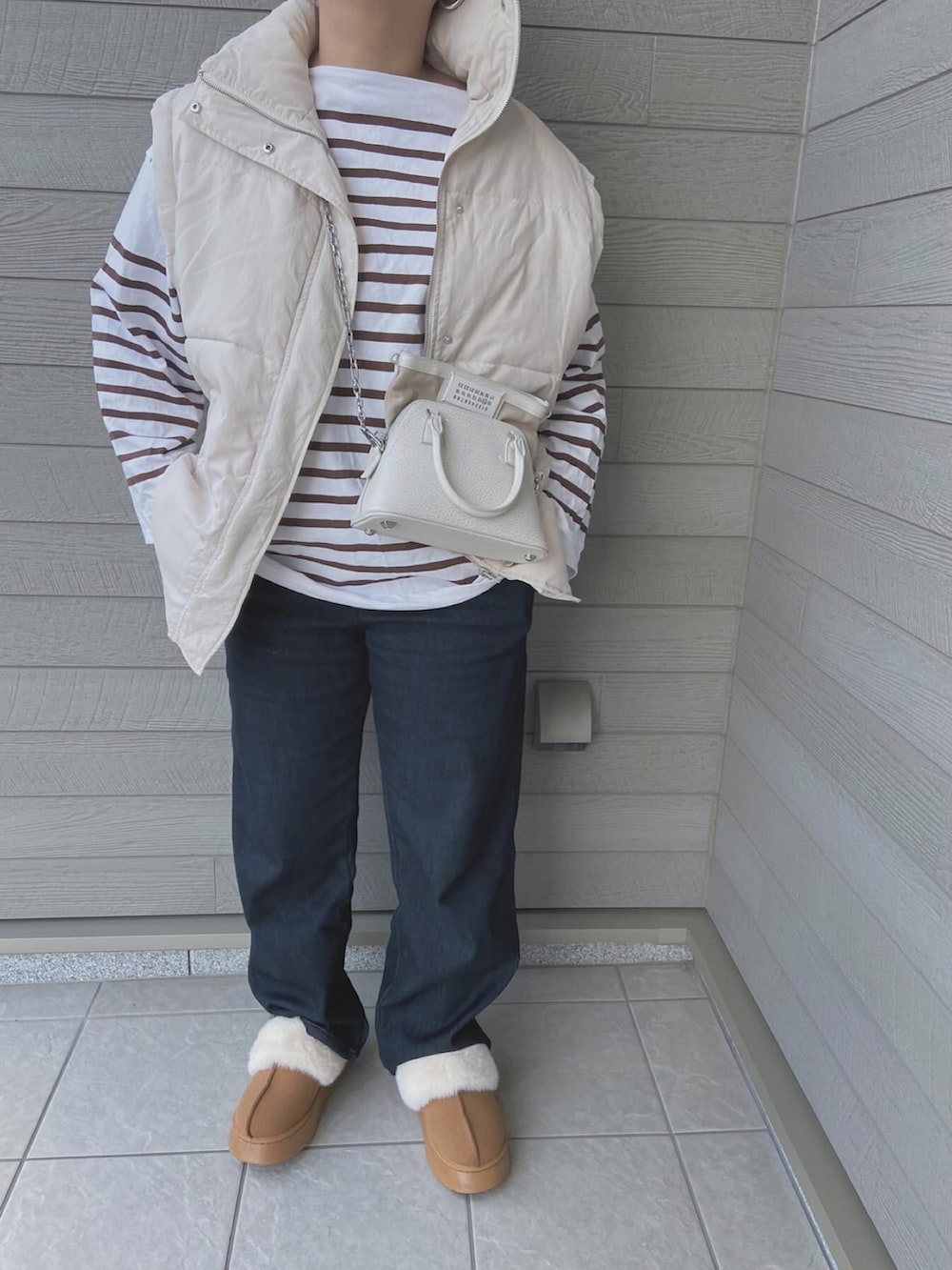 ホワイト系のダウンベスト、ブラウン系のTシャツ/カットソー、ホワイト系のショルダーバッグを着用したレディースの秋コーディネートの3枚目の写真