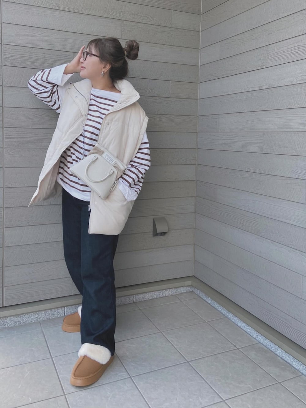 ホワイト系のダウンベスト、ブラウン系のTシャツ/カットソー、ホワイト系のショルダーバッグを着用したレディースの秋コーディネートの2枚目の写真