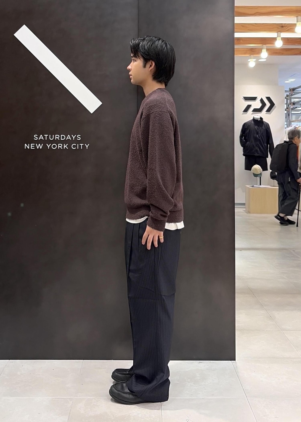 ブラウン系のニット/セーター、ブルー系のスラックスを着用したメンズの秋コーディネートの3枚目の写真