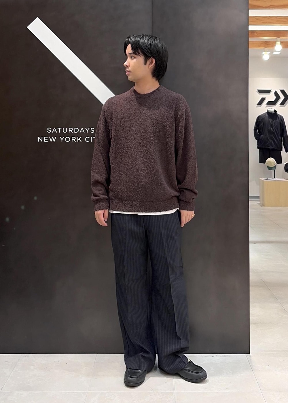 ブラウン系のニット/セーター、ブルー系のスラックスを着用したメンズの秋コーディネートの2枚目の写真