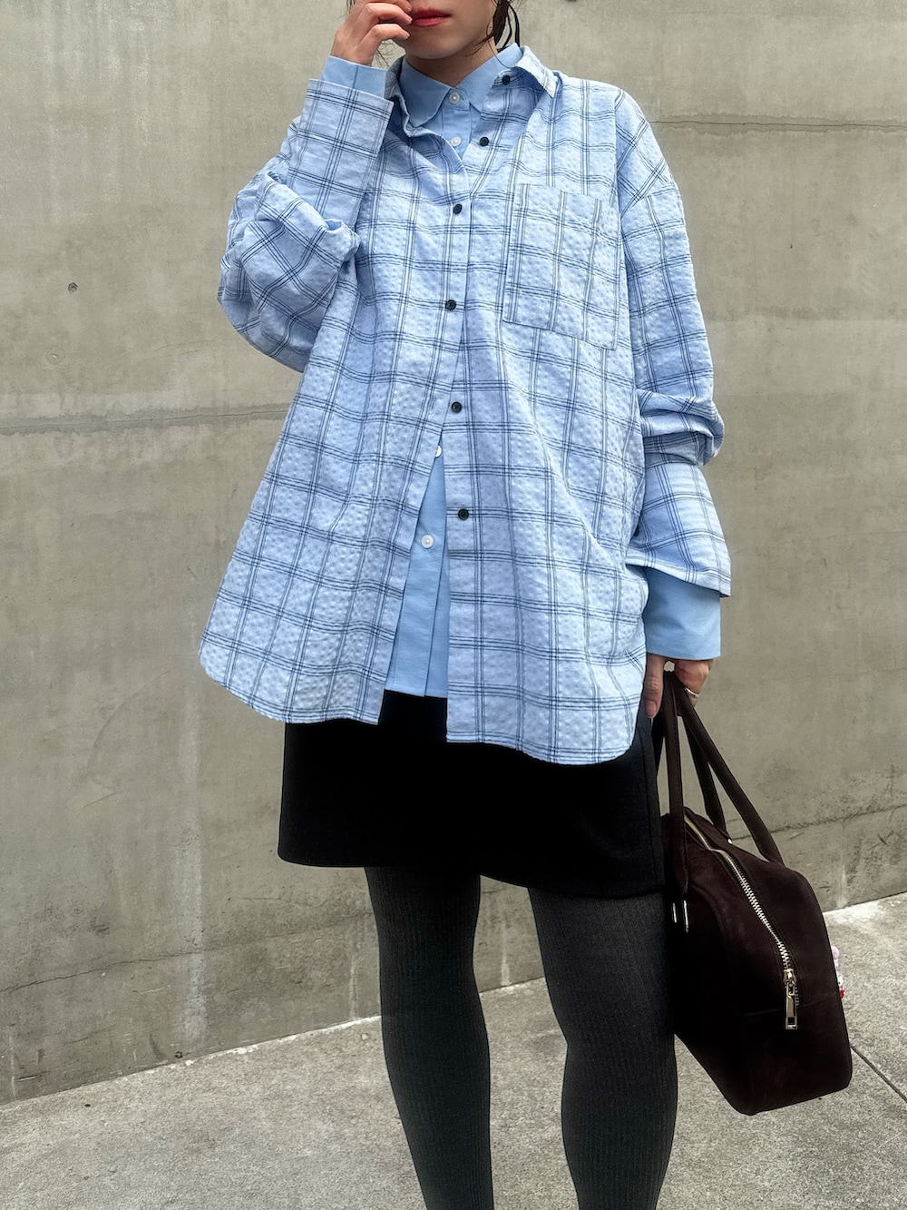 グレー系のスカート、ブルー系のシャツ/ブラウス、ブラウン系のボストンバッグを着用したレディースの春コーディネートの2枚目の写真