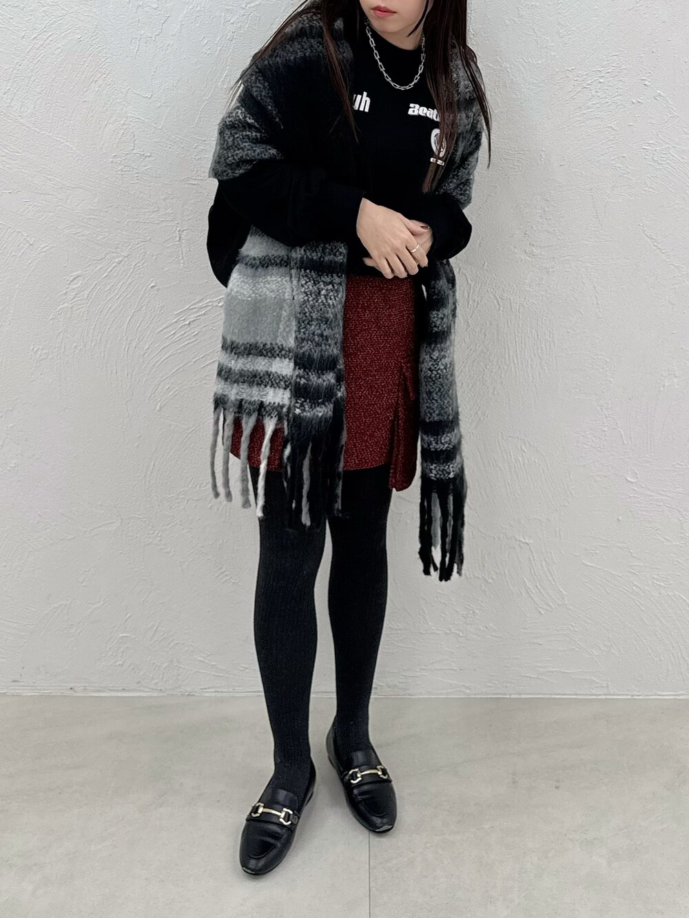 レッド系のスカート、ブラック系のスウェットを着用したレディースの秋コーディネートの2枚目の写真
