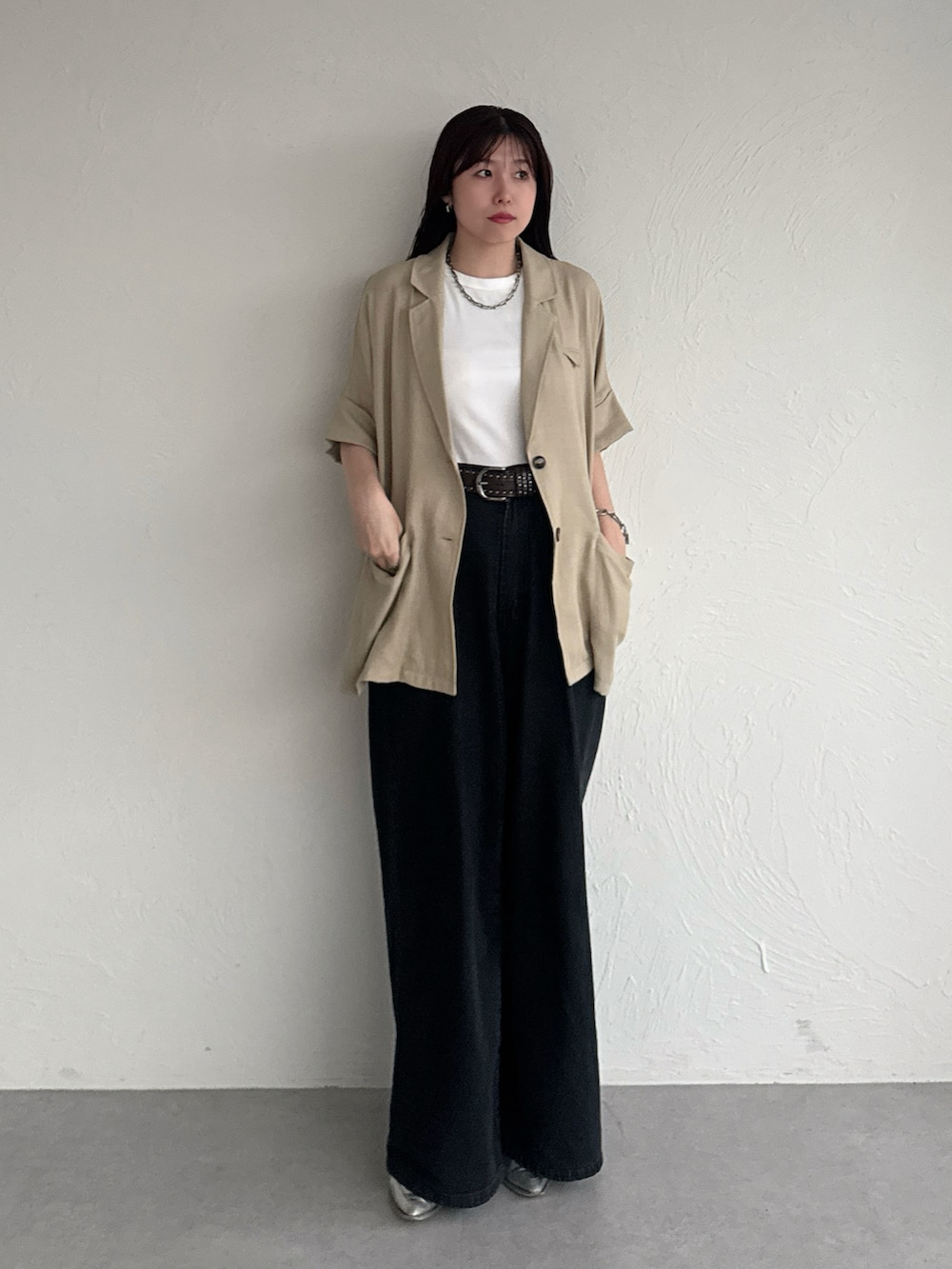 ベージュ系のテーラードジャケット、ブラック系のデニムパンツ、ブラウン系のベルトを着用したレディースの夏コーディネートの2枚目の写真