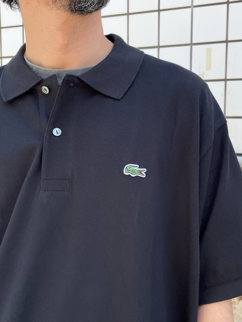 ブラック系のポロシャツ、ホワイト系のパンツ、ブラック系のモカシン/デッキシューズを着用したメンズの夏コーディネートの5枚目の写真