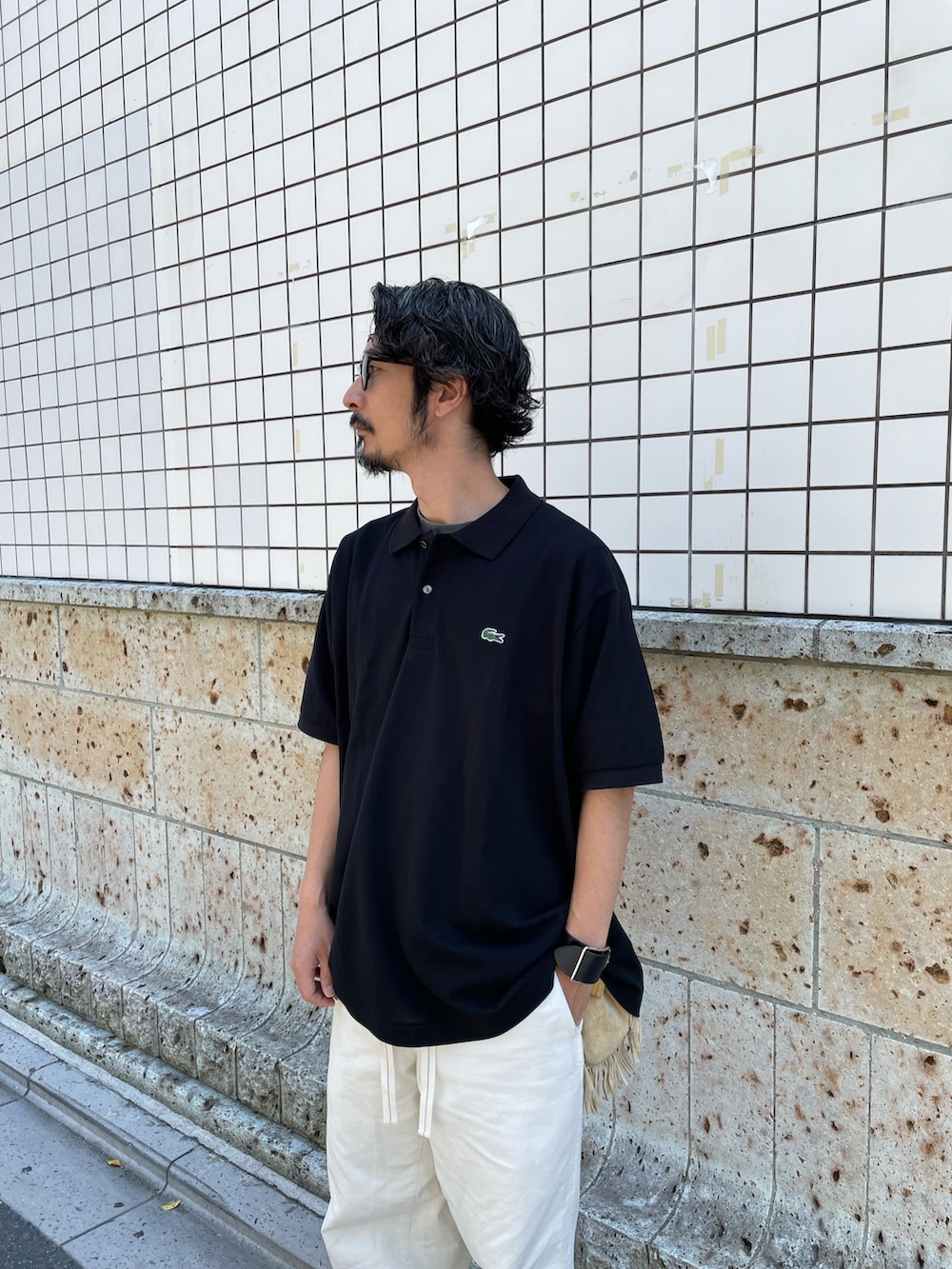 ブラック系のポロシャツ、ホワイト系のパンツ、ブラック系のモカシン/デッキシューズを着用したメンズの夏コーディネートの2枚目の写真