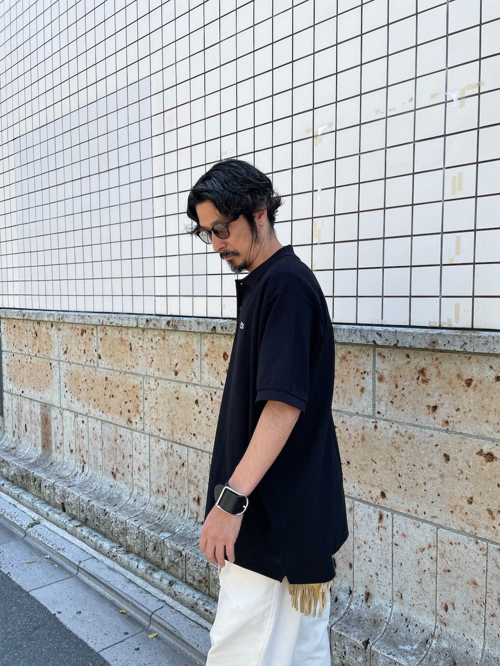 ブラック系のポロシャツ、ホワイト系のパンツ、ブラック系のモカシン/デッキシューズを着用したメンズの夏コーディネートの4枚目の写真