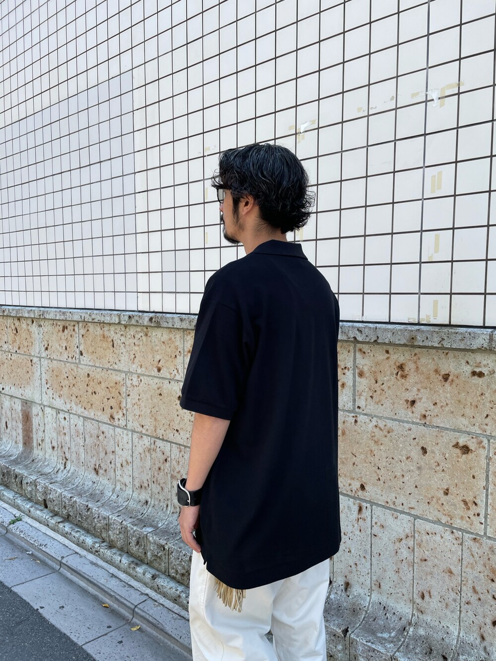 ブラック系のポロシャツ、ホワイト系のパンツ、ブラック系のモカシン/デッキシューズを着用したメンズの夏コーディネートの3枚目の写真