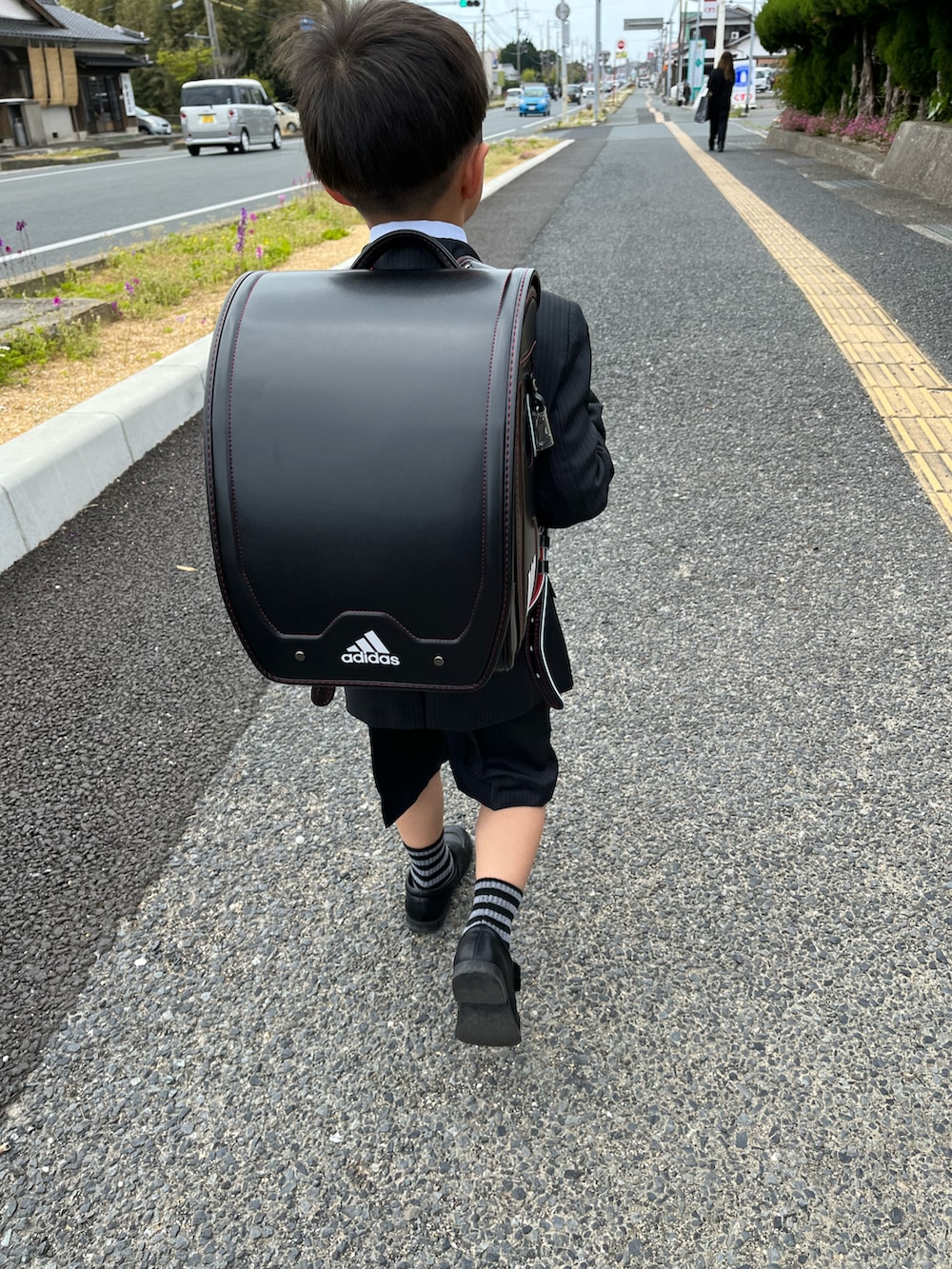 ブルー系のスカート、ブラック系のランドセル、ブルー系のノーカラージャケットを着用したキッズの春コーディネートの2枚目の写真