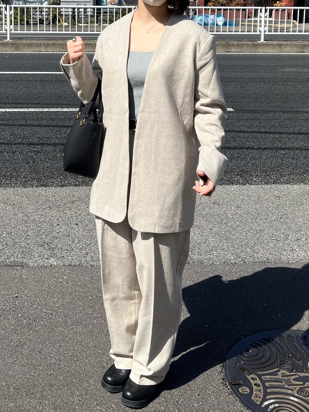 ベージュ系のノーカラージャケット、ベージュ系のスラックス、ブラック系のショルダーバッグを着用したレディースの秋コーディネートの2枚目の写真