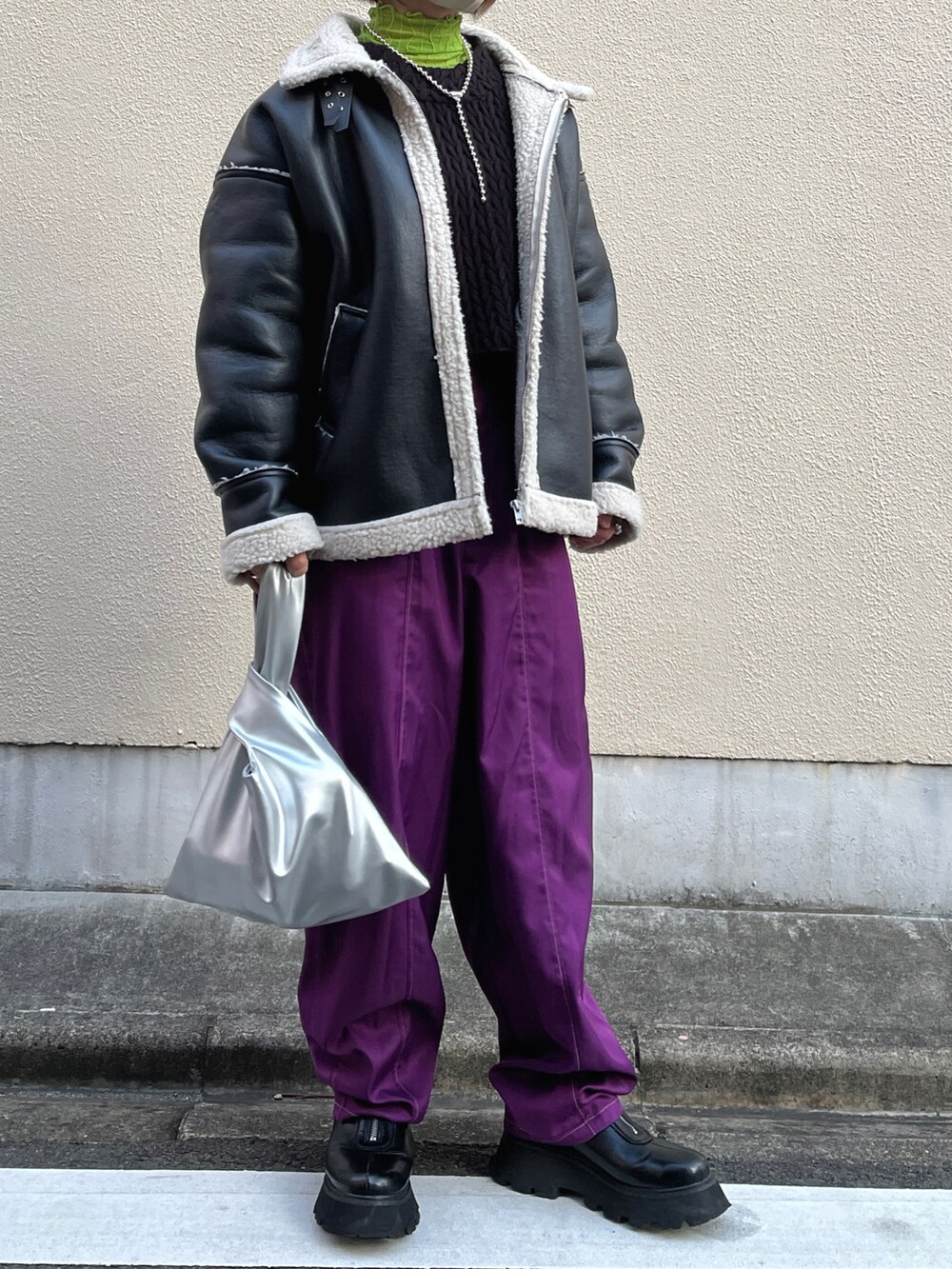パープル系のスラックス、ブラック系のブーツ、ブラック系のブルゾンを着用したレディースの冬コーディネートの2枚目の写真