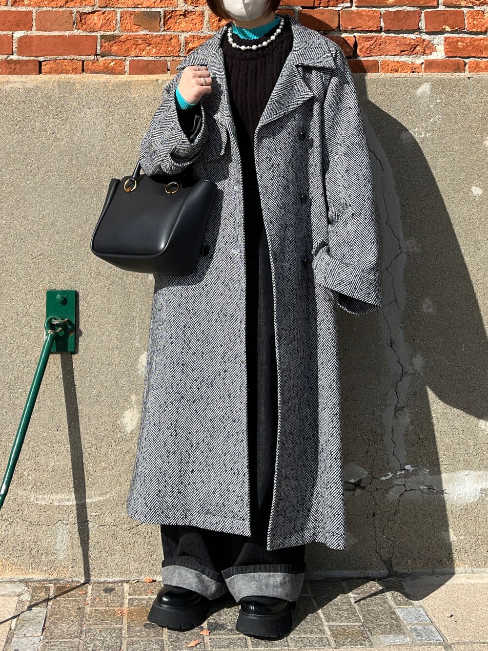 ブラック系のニット/セーター、グリーン系のニット/セーター、ブラック系のチェスターコートを着用したレディースの冬コーディネートの2枚目の写真