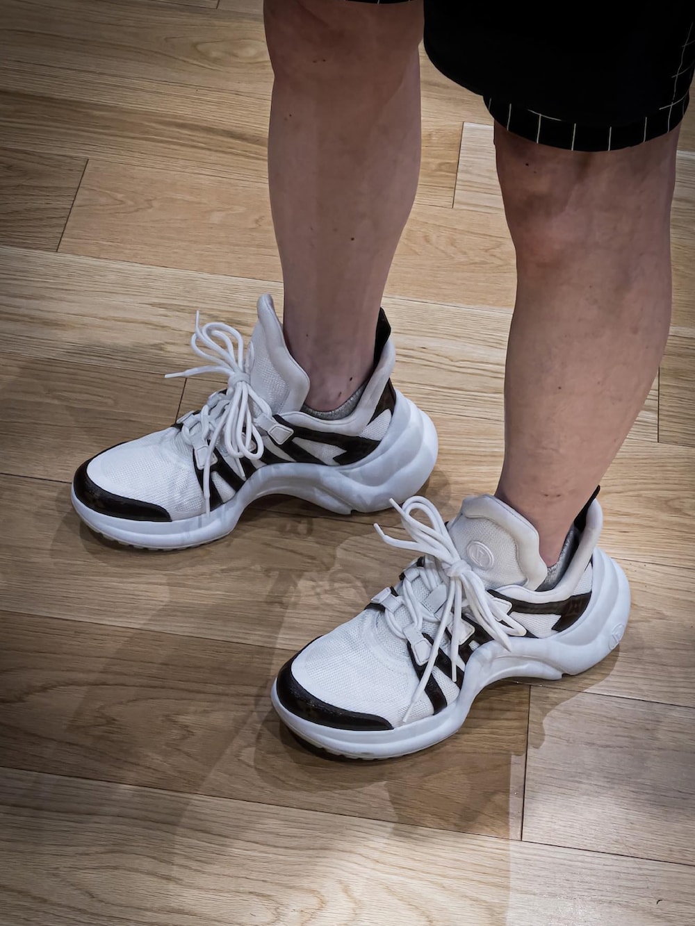 ホワイト系のスニーカー、ブラック系のTシャツ/カットソー、ベージュ系のキャップを着用したメンズの夏コーディネートの3枚目の写真