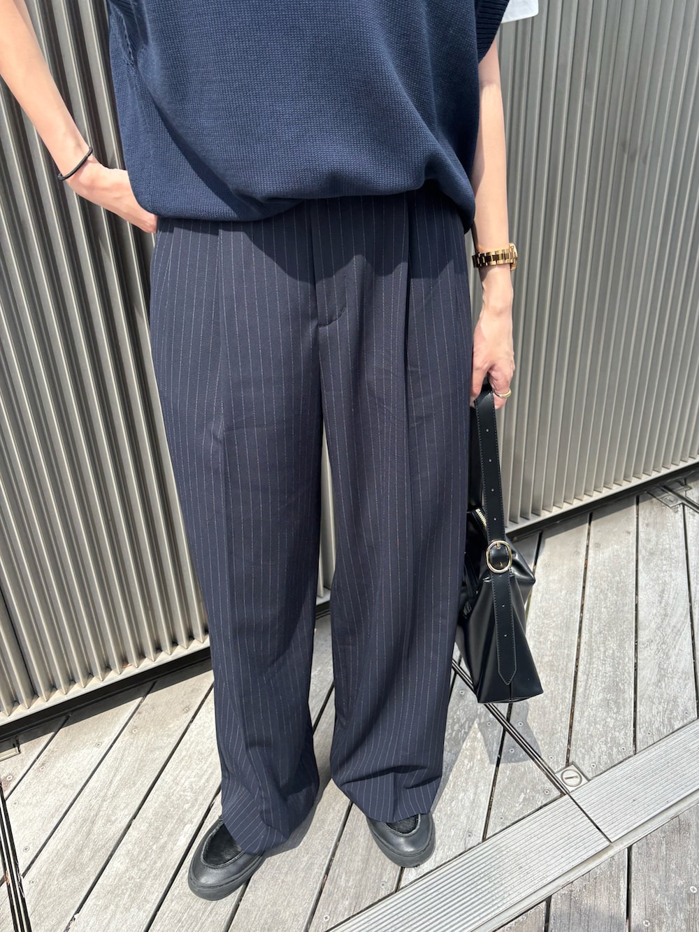 ブラック系のハンドバッグ、ブルー系のパンツ、ブラック系のスニーカーを着用したレディースの夏コーディネートの3枚目の写真