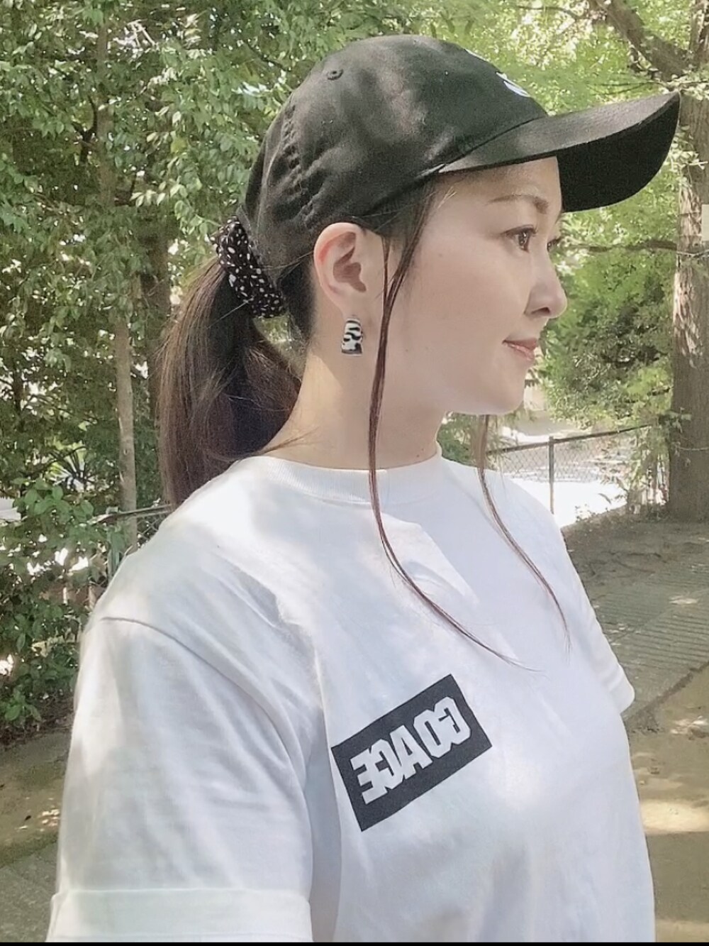 ホワイト系のTシャツ/カットソー、ホワイト系のスカート、ブラック系のサンダルを着用したレディースの夏コーディネートの4枚目の写真