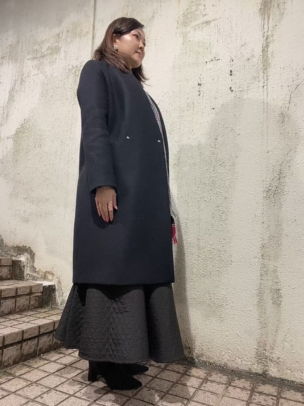 ブラック系のスカート、グリーン系のニット/セーター、ブラック系のブーツを着用したレディースの冬コーディネートの4枚目の写真