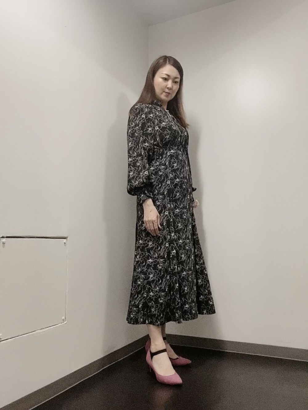 ブラック系のワンピース、ピンク系のパンプス、ホワイト系のピアス（両耳用）を着用したレディースの春コーディネートの2枚目の写真