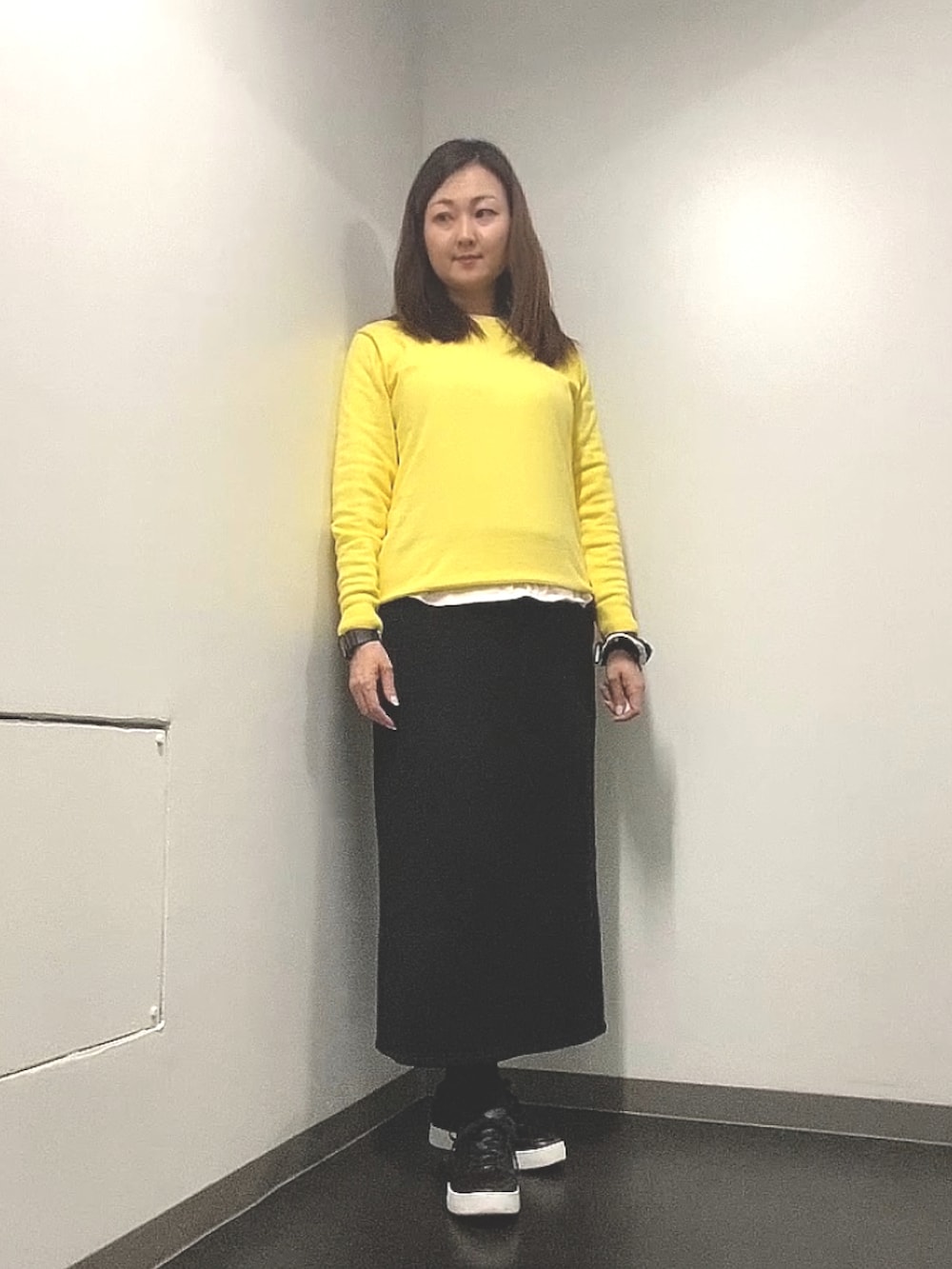 ベージュ系のトレンチコート、イエロー系のニット/セーター、ホワイト系のTシャツ/カットソーを着用したレディースの春コーディネートの2枚目の写真