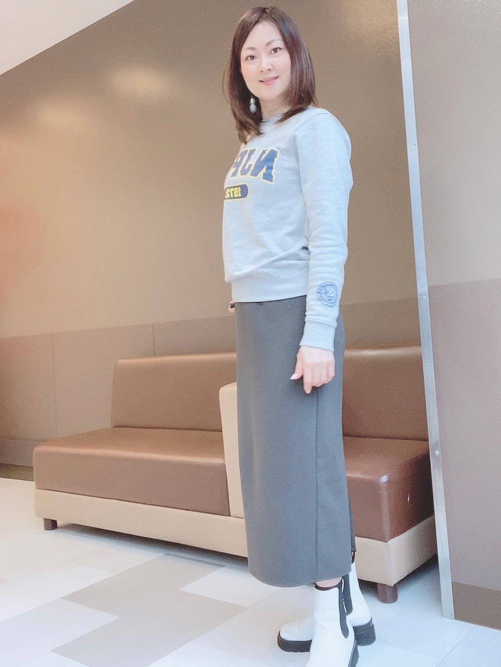 グレー系のスカート、ホワイト系のレインシューズ、グレー系のスウェットを着用したレディースの春コーディネートの2枚目の写真