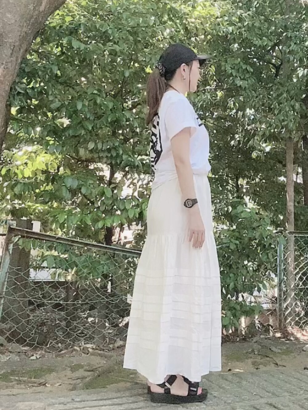 ホワイト系のTシャツ/カットソー、ホワイト系のスカート、ブラック系のサンダルを着用したレディースの夏コーディネートの3枚目の写真