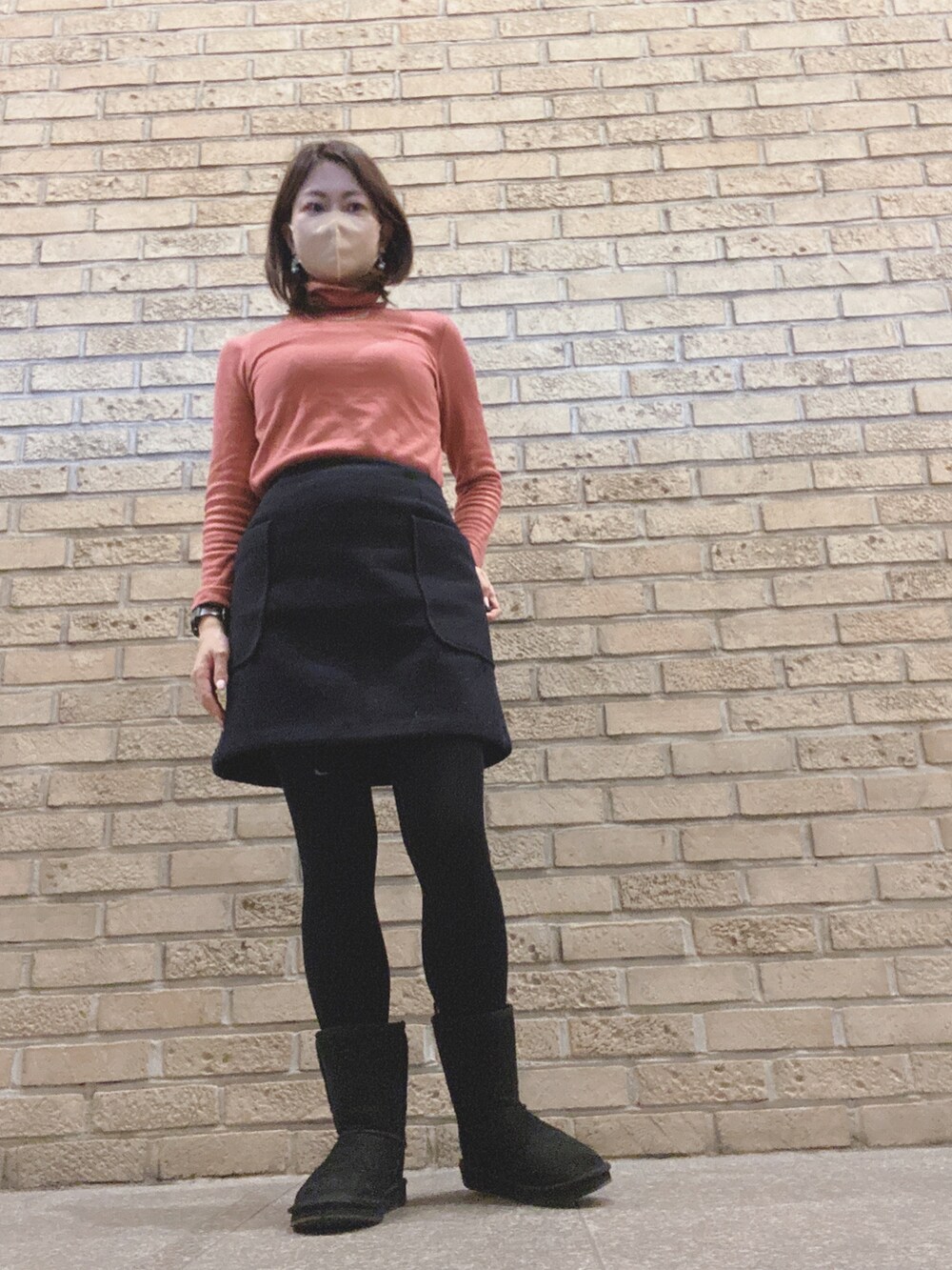 ピンク系のダウンジャケット/コート、ピンク系のTシャツ/カットソー、ブルー系のスカートを着用したレディースの冬コーディネートの2枚目の写真