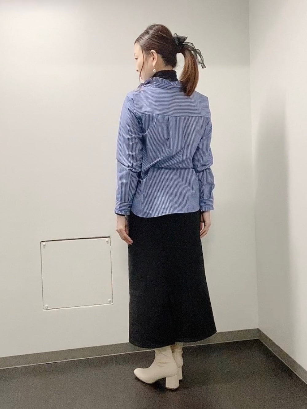 ブラック系のスカート、ホワイト系のブーツ、ブルー系のシャツ/ブラウスを着用したレディースの冬コーディネートの3枚目の写真