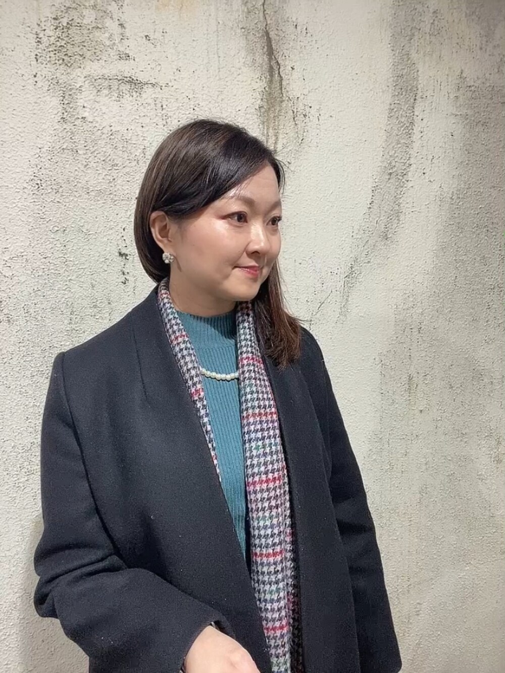 ブラック系のスカート、グリーン系のニット/セーター、ブラック系のブーツを着用したレディースの冬コーディネートの5枚目の写真