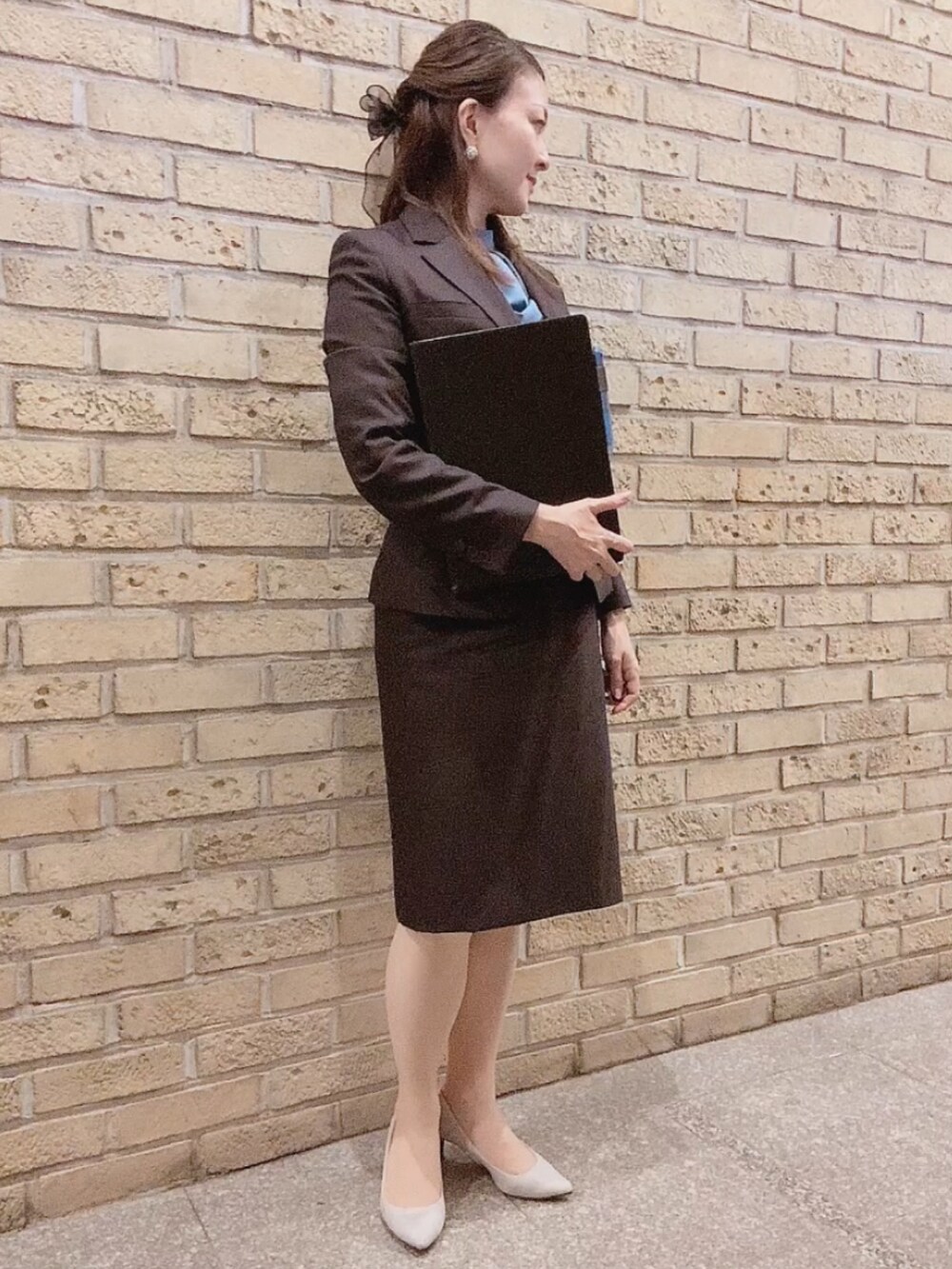 ブラウン系のスーツセット、グレー系のパンプス、ブルー系のシャツ/ブラウスを着用したレディースの秋コーディネートの3枚目の写真