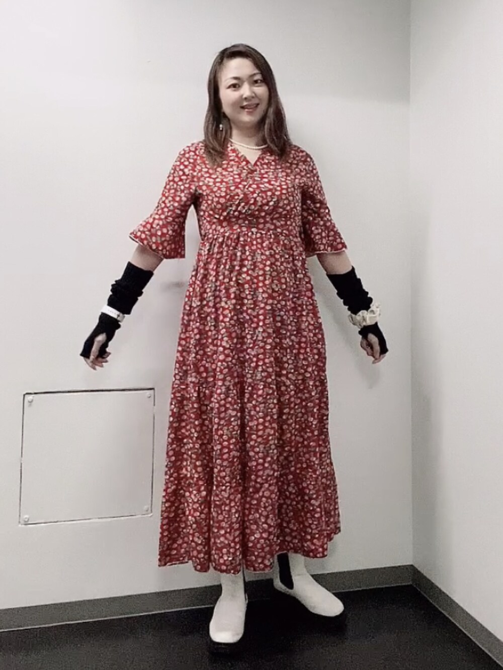 レッド系のワンピース、ホワイト系のレインシューズ、ブラック系のアームカバーを着用したレディースの秋コーディネートの3枚目の写真