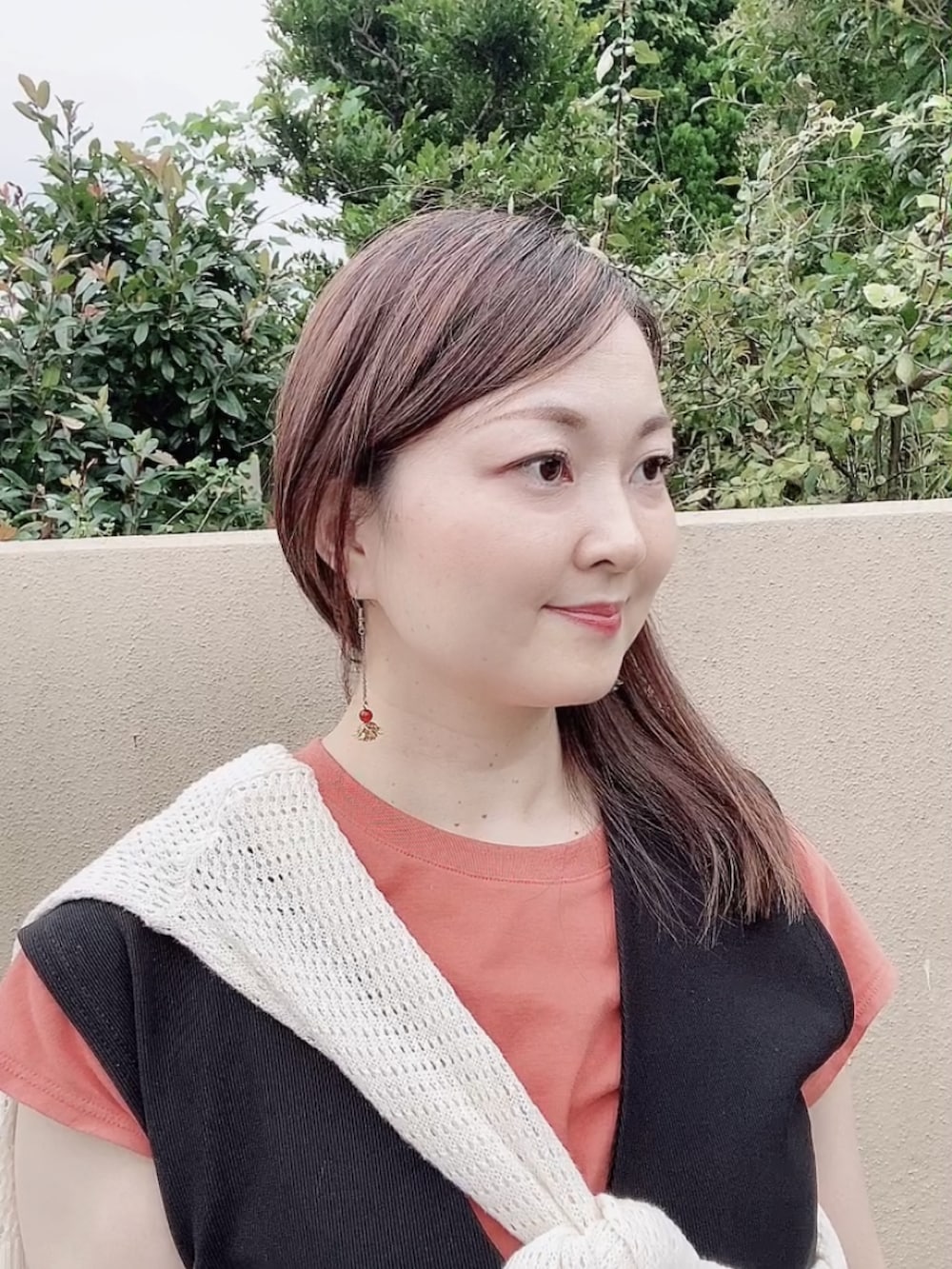 ブラック系のジャンパースカート、ホワイト系のカーディガン/ボレロ、オレンジ系のTシャツ/カットソーを着用したレディースの秋コーディネートの5枚目の写真
