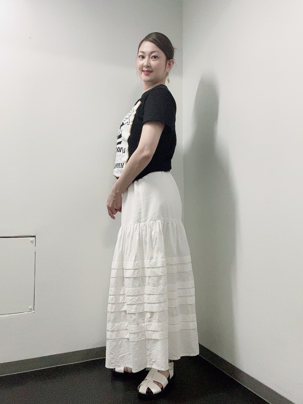 ブラック系のTシャツ/カットソー、ホワイト系のスカート、ホワイト系のサンダルを着用したレディースの夏コーディネートの2枚目の写真