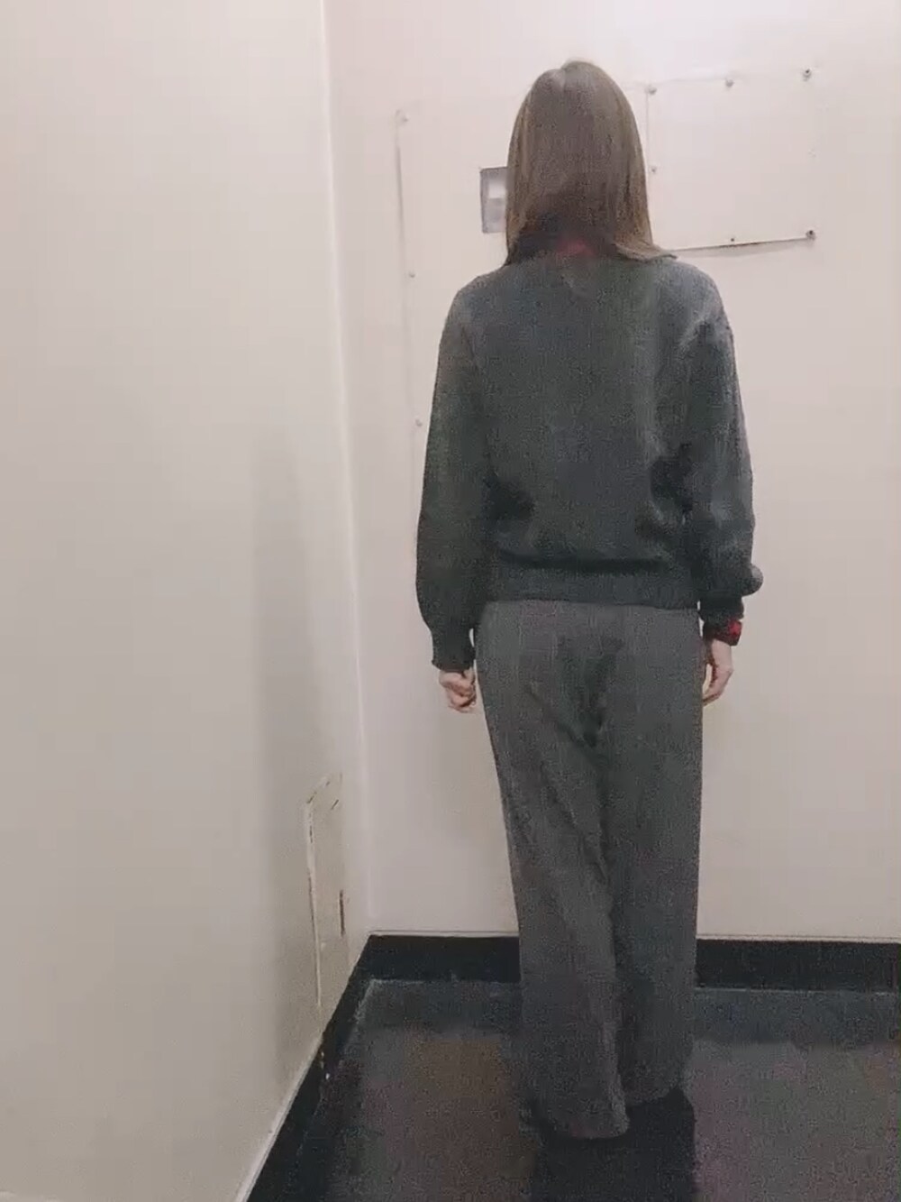 レッド系のニット/セーター、グレー系のスラックス、ブラック系のモカシン/デッキシューズを着用したレディースの冬コーディネートの4枚目の写真