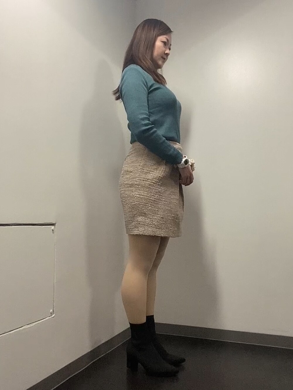 ブラック系のダウンジャケット/コート、グリーン系のニット/セーター、ベージュ系のスカートを着用したレディースの冬コーディネートの3枚目の写真