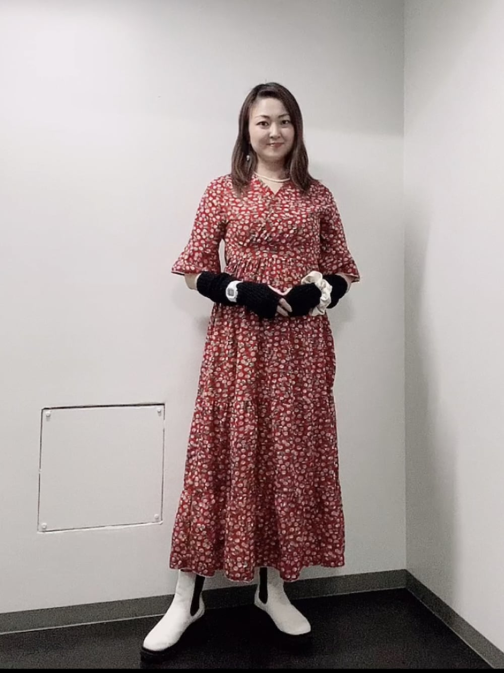 レッド系のワンピース、ホワイト系のレインシューズ、ブラック系のアームカバーを着用したレディースの秋コーディネートの2枚目の写真