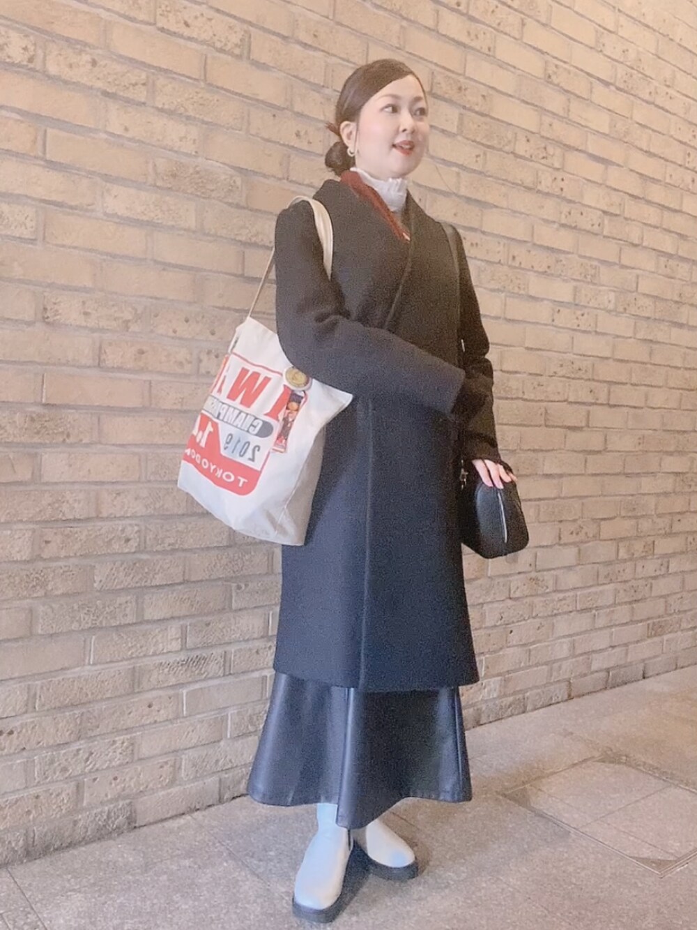 グレー系のTシャツ/カットソー、ブラック系のスカート、ホワイト系のレインシューズを着用したレディースの冬コーディネートの2枚目の写真