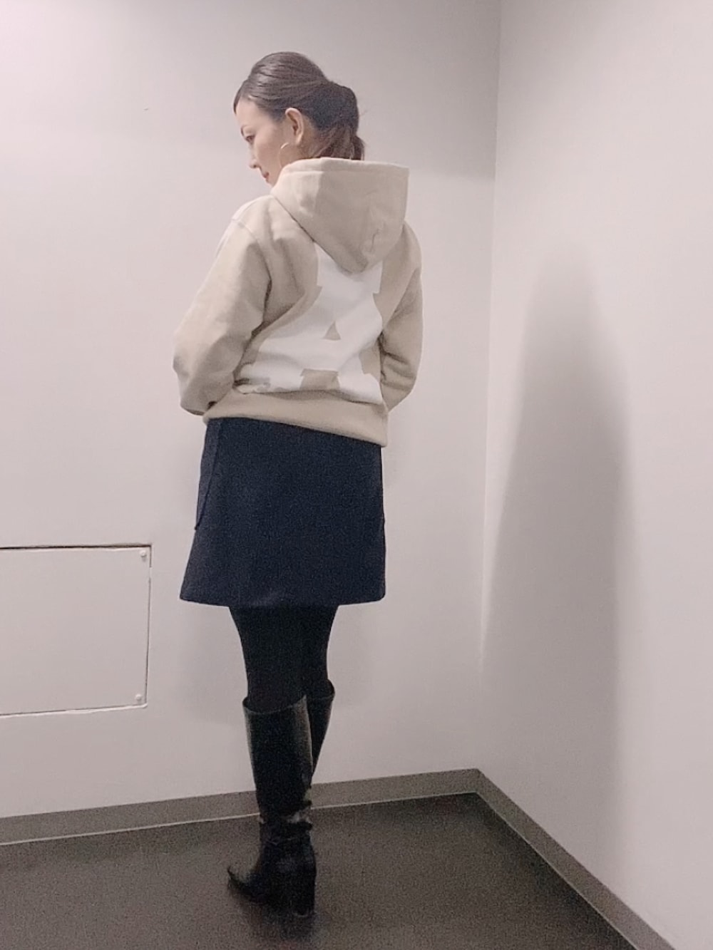 ベージュ系のパーカー、ブルー系のスカート、ブラック系のブーツを着用したレディースの冬コーディネートの3枚目の写真