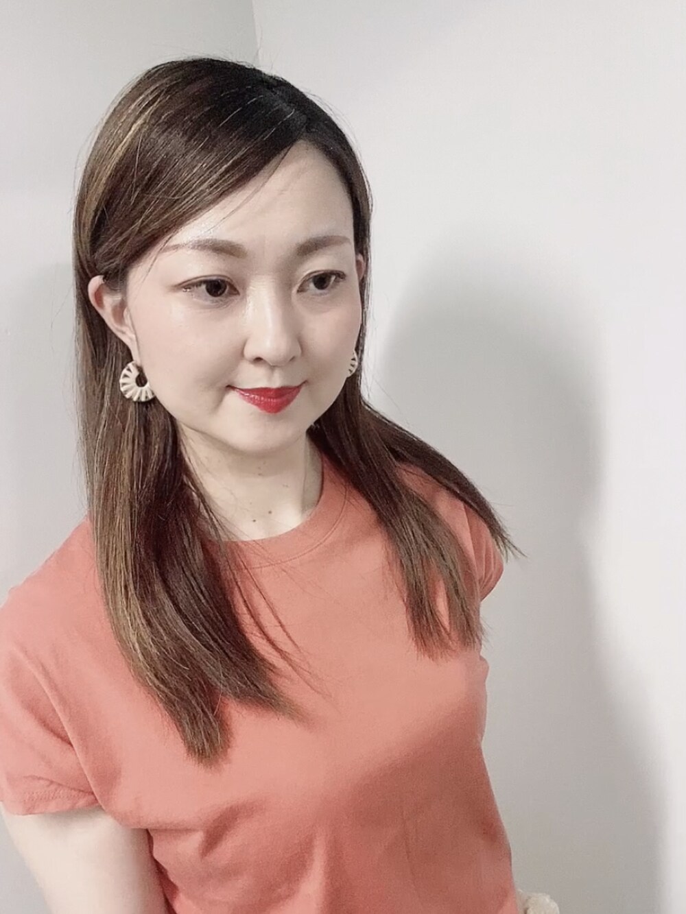 オレンジ系のTシャツ/カットソー、ホワイト系のスカート、ホワイト系のサンダルを着用したレディースの夏コーディネートの4枚目の写真