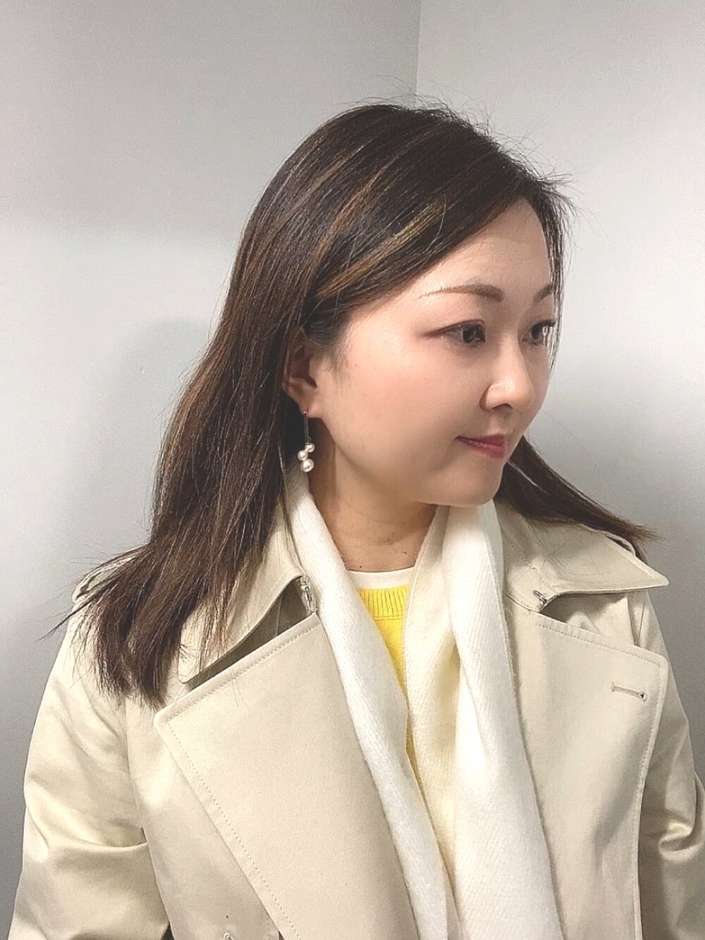 ベージュ系のトレンチコート、イエロー系のニット/セーター、ホワイト系のTシャツ/カットソーを着用したレディースの春コーディネートの5枚目の写真