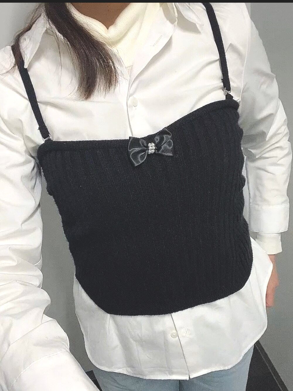 ブラック系のニット/セーター、ホワイト系のシャツ/ブラウス、ブルー系のデニムパンツを着用したレディースの春コーディネートの4枚目の写真