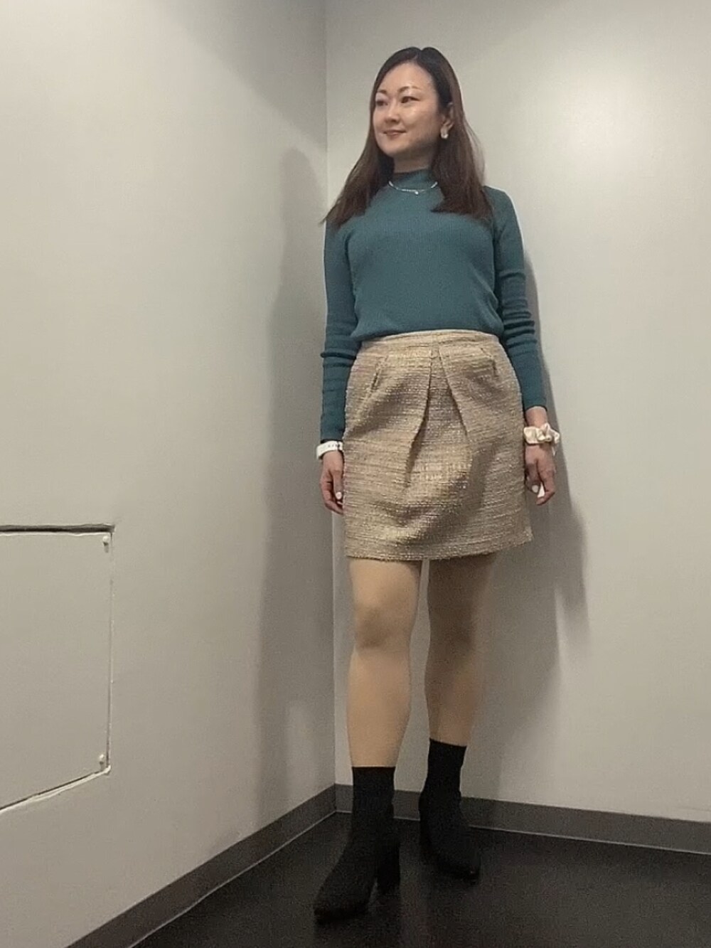 ブラック系のダウンジャケット/コート、グリーン系のニット/セーター、ベージュ系のスカートを着用したレディースの冬コーディネートの2枚目の写真